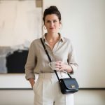 Woman in neutral minimalist outfit wearing a small black leather crossbody bag