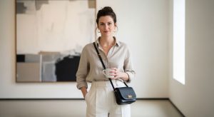 Woman in neutral minimalist outfit wearing a small black leather crossbody bag