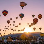 Hundreds of colorful hot air balloons rising over Balloon Fiesta Park at sunrise in Albuquerque, New Mexico during the 2026 International Balloon Fiesta